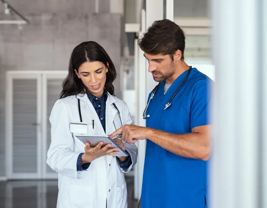 Nurse teacher reviewing patient charts with nursing student in blue scrubs